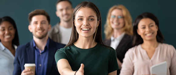 a group of people on a dark green background with the lady in front outstretching her hand to the viewer