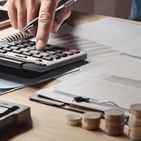 an accountant using a calculator while overlooking papers with coins stacked in front of them