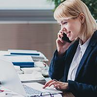 a lady in office on the phone, typing on a laptop while sorting files as part of administration duties 