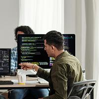 four IT developers sitting at a desk in front of computers in discussion